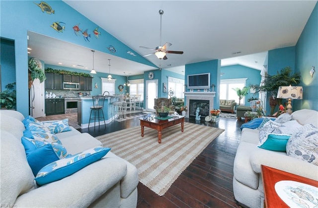 living area featuring a fireplace, vaulted ceiling, dark wood-style floors, and ceiling fan