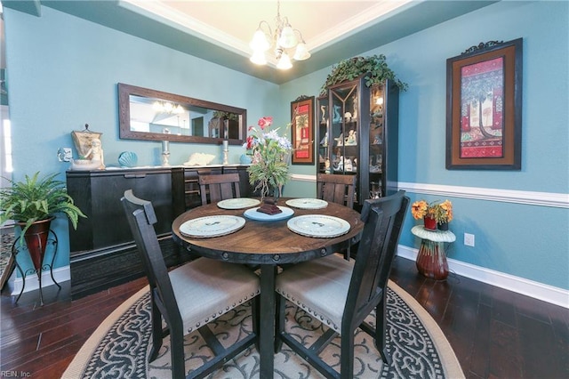 dining room with a raised ceiling, dark hardwood / wood-style floors, and a notable chandelier