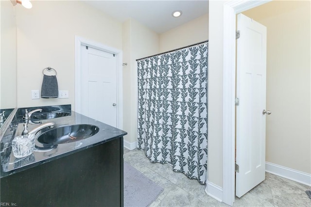 full bathroom featuring a shower with shower curtain, baseboards, and a sink