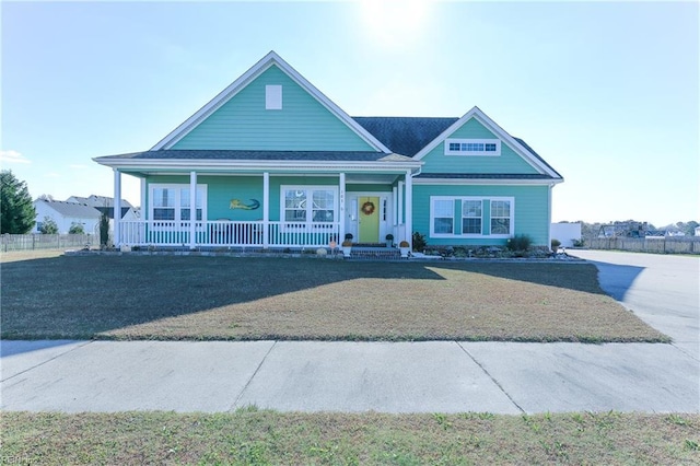 view of front facade featuring a porch, a front yard, and fence