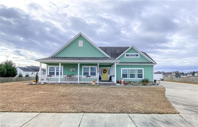 view of front of property featuring a porch, concrete driveway, and fence