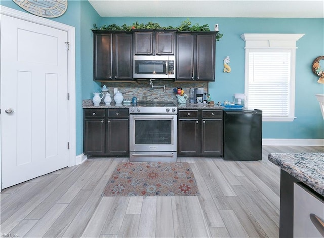 kitchen featuring backsplash, stainless steel appliances, light wood-style floors, stone counters, and dark brown cabinets