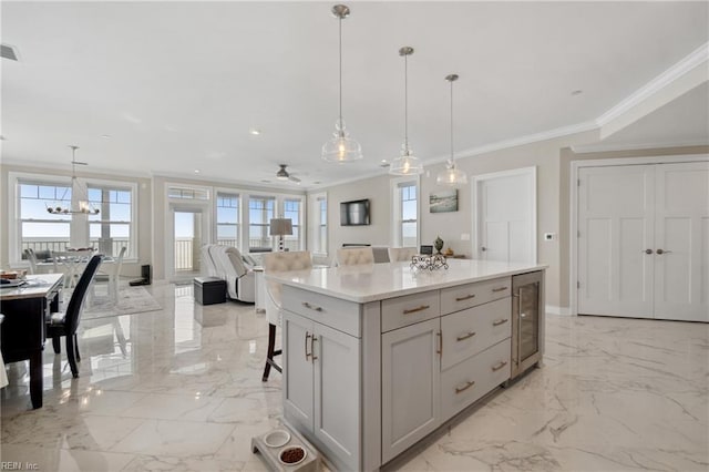 kitchen with decorative light fixtures, a breakfast bar area, a kitchen island, ceiling fan with notable chandelier, and ornamental molding