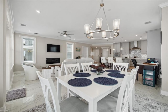 dining area with ceiling fan with notable chandelier and ornamental molding