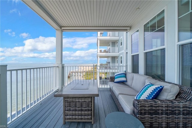 balcony with an outdoor living space and a water view