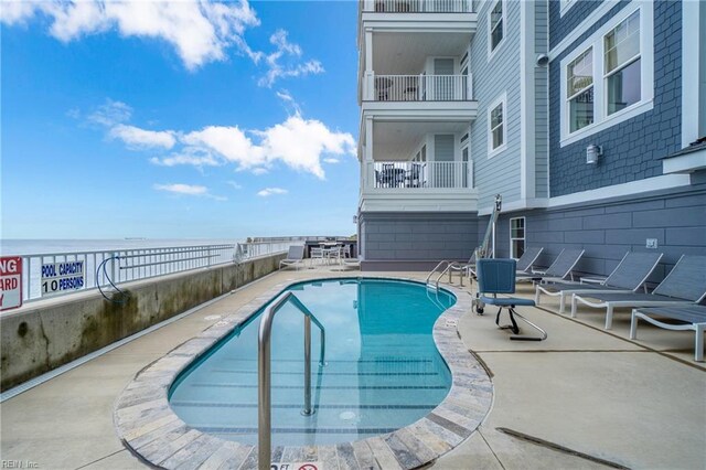 view of pool with a water view and a patio area