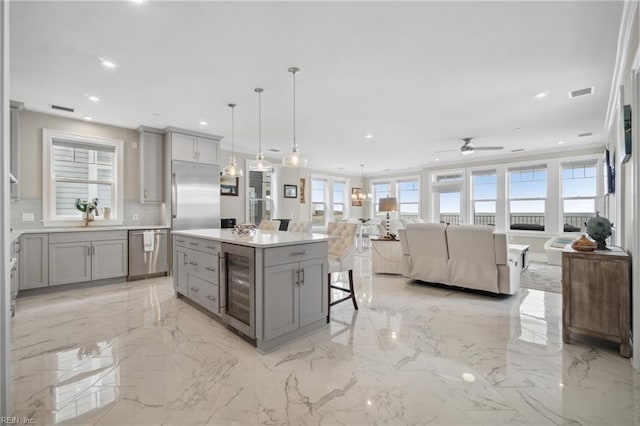 kitchen featuring gray cabinetry, a kitchen island, hanging light fixtures, and appliances with stainless steel finishes