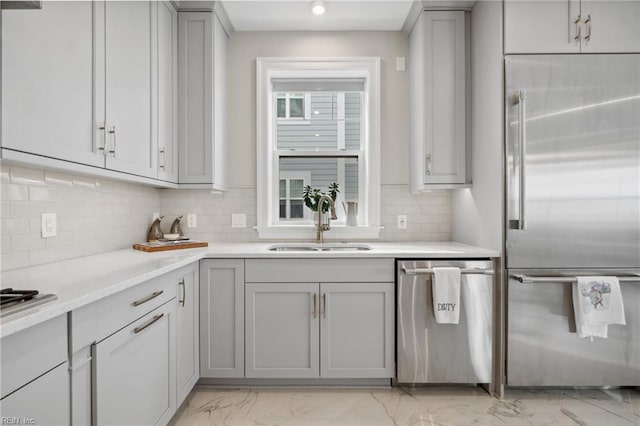 kitchen with appliances with stainless steel finishes, backsplash, gray cabinetry, and sink