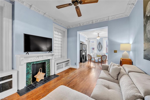 living room featuring a tiled fireplace, ceiling fan, and hardwood / wood-style floors