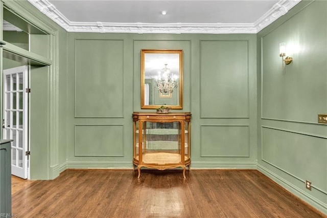 sitting room featuring dark hardwood / wood-style floors, ornamental molding, and an inviting chandelier