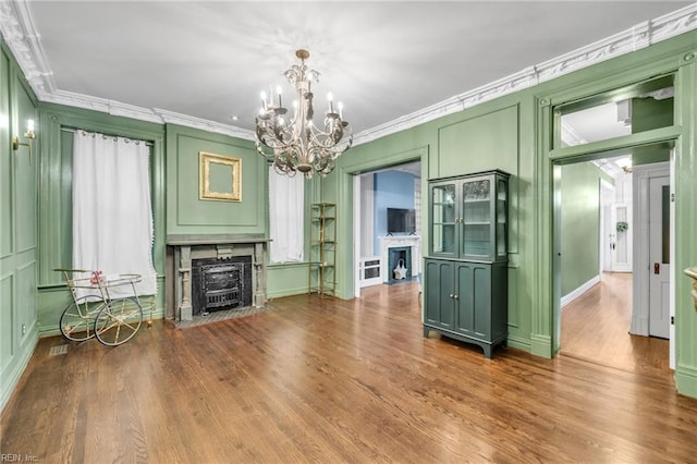 unfurnished living room featuring a notable chandelier, wood-type flooring, and crown molding