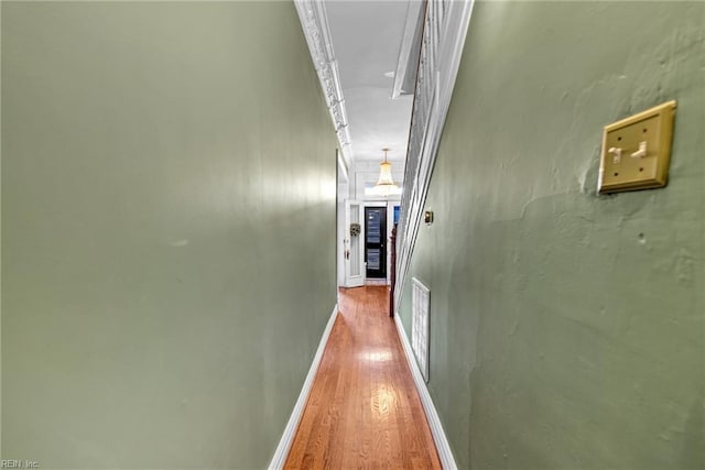 corridor with ornamental molding and light hardwood / wood-style flooring