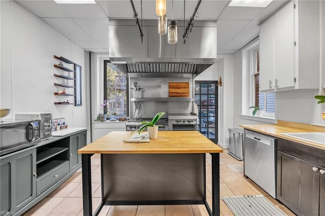 kitchen with white cabinetry, a breakfast bar, hanging light fixtures, and stainless steel dishwasher