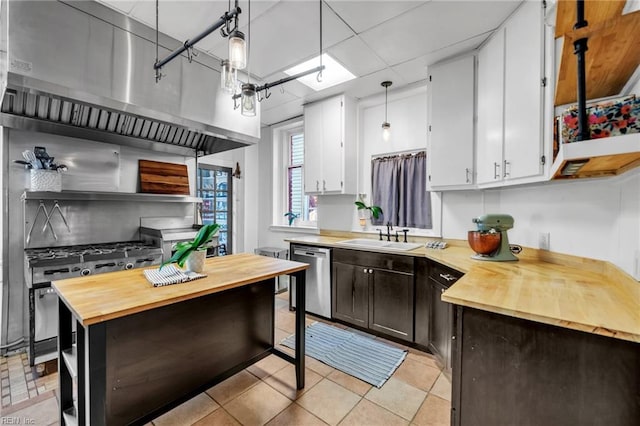 kitchen featuring dishwasher, sink, hanging light fixtures, light tile patterned floors, and white cabinetry