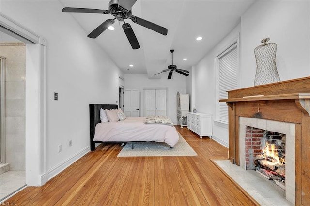 bedroom with ceiling fan, hardwood / wood-style floors, ensuite bathroom, and lofted ceiling