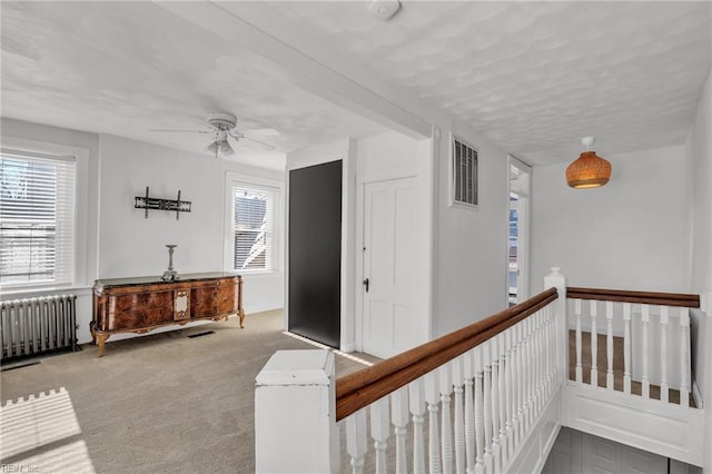 corridor featuring light colored carpet and radiator