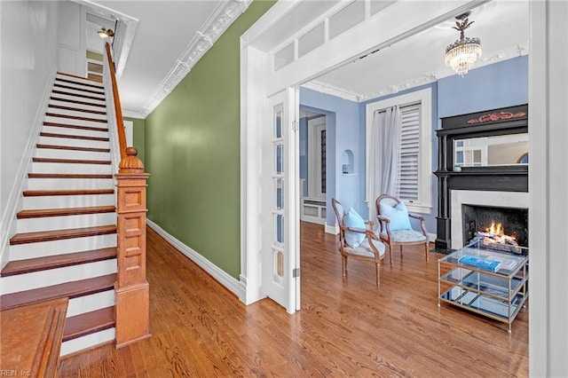 staircase with an inviting chandelier, wood-type flooring, and ornamental molding