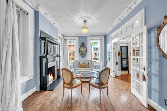 sitting room featuring wood-type flooring and ornamental molding