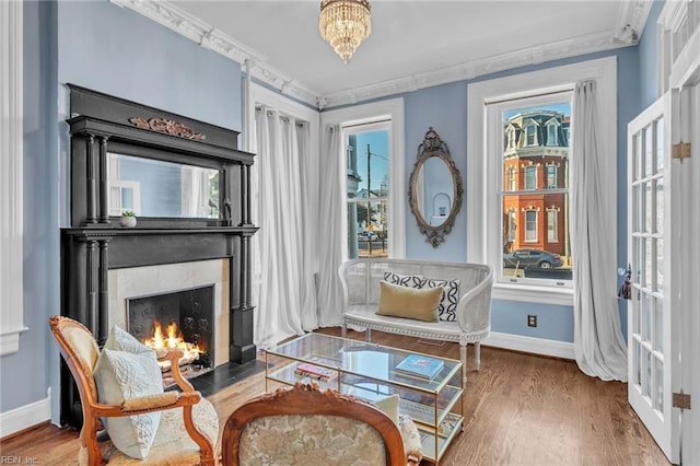 living area with crown molding, hardwood / wood-style floors, and a notable chandelier