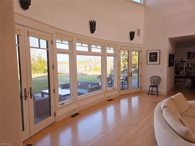 doorway featuring french doors, light hardwood / wood-style flooring, and a high ceiling