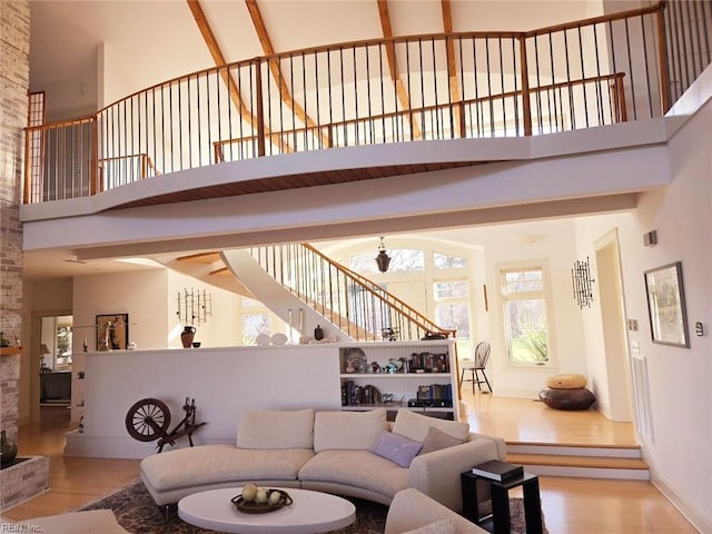 living room featuring a high ceiling, light wood-type flooring, and beam ceiling