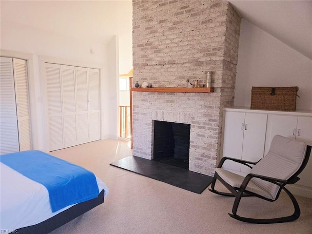 bedroom featuring a brick fireplace, vaulted ceiling, and two closets