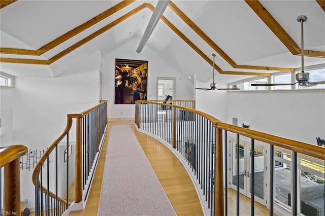 hallway with lofted ceiling with beams, light wood-type flooring, and a wealth of natural light