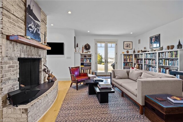 living room with french doors, hardwood / wood-style floors, and a brick fireplace