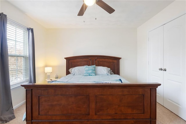 carpeted bedroom with ceiling fan and a closet