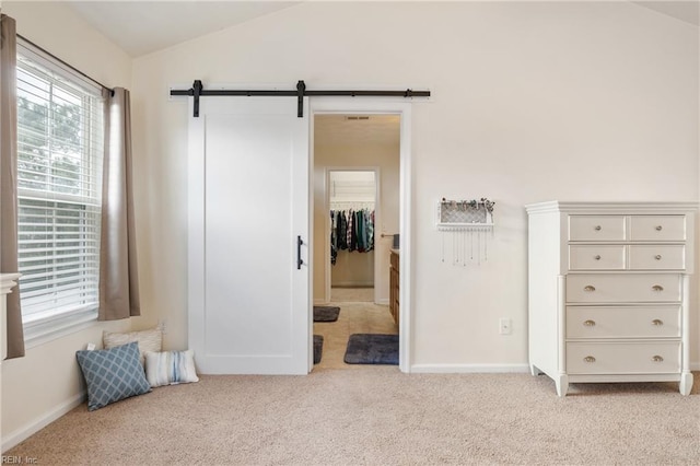 bedroom with a barn door, lofted ceiling, light carpet, and a closet