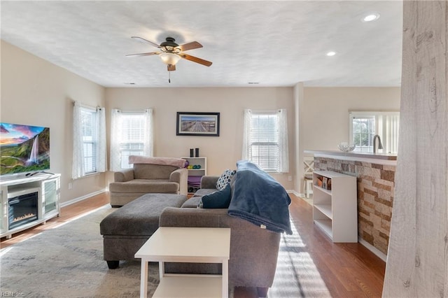 living room featuring ceiling fan, light hardwood / wood-style floors, and a wealth of natural light