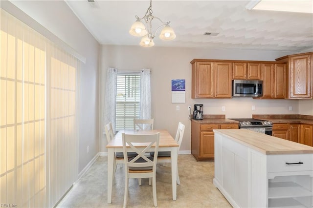 kitchen featuring butcher block counters, a chandelier, hanging light fixtures, and appliances with stainless steel finishes