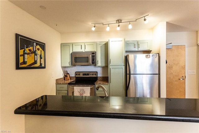 kitchen featuring backsplash, kitchen peninsula, stainless steel appliances, and green cabinetry