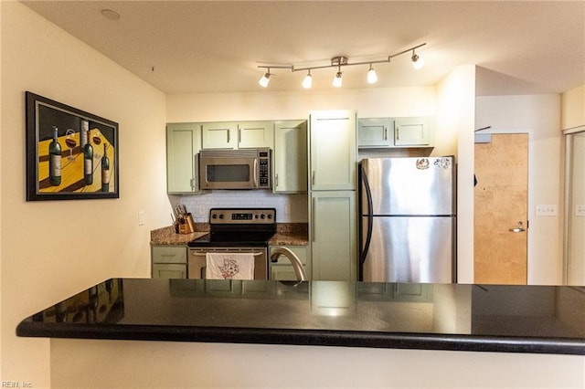 kitchen featuring sink, stainless steel appliances, green cabinets, kitchen peninsula, and decorative backsplash