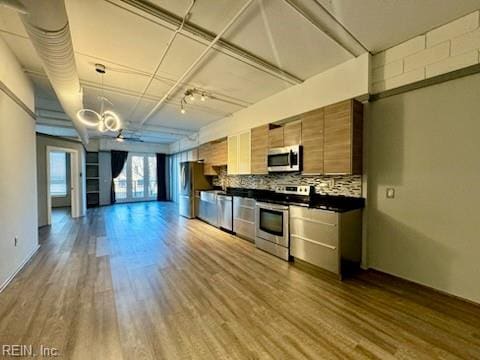 kitchen with ceiling fan, stainless steel appliances, decorative light fixtures, decorative backsplash, and hardwood / wood-style flooring