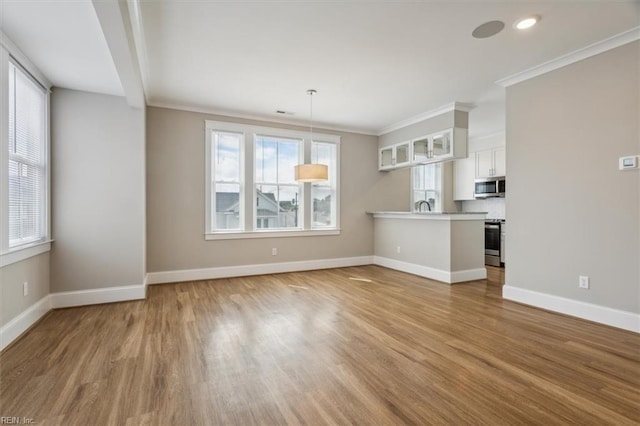 unfurnished living room with hardwood / wood-style flooring, ornamental molding, and sink