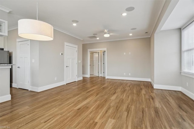 unfurnished living room with hardwood / wood-style floors, a wealth of natural light, ceiling fan, and crown molding