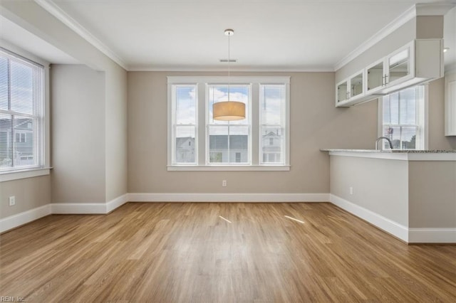 unfurnished dining area featuring crown molding and light wood-type flooring