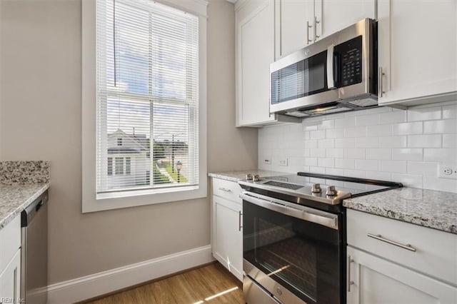 kitchen with light stone countertops, white cabinets, and stainless steel appliances