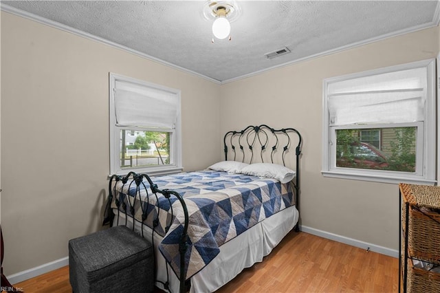 bedroom featuring a textured ceiling, light hardwood / wood-style flooring, ceiling fan, and ornamental molding