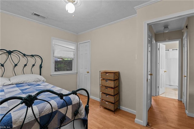 bedroom featuring a textured ceiling, light wood-type flooring, ceiling fan, and ornamental molding