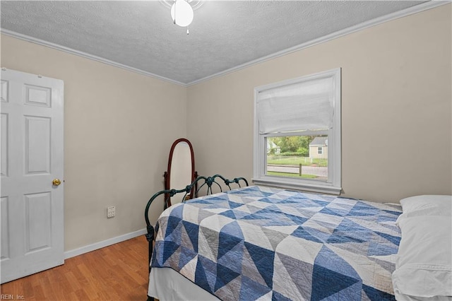 bedroom featuring crown molding, wood-type flooring, and a textured ceiling