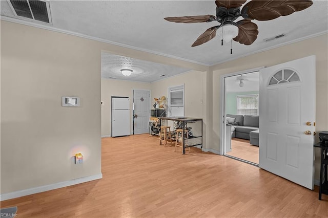 foyer entrance with light hardwood / wood-style floors, a textured ceiling, and ornamental molding