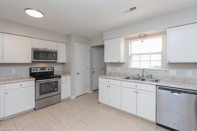 kitchen featuring white cabinets, appliances with stainless steel finishes, light tile patterned floors, and sink