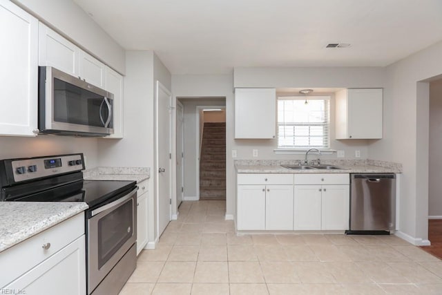 kitchen with light stone counters, sink, white cabinets, and stainless steel appliances