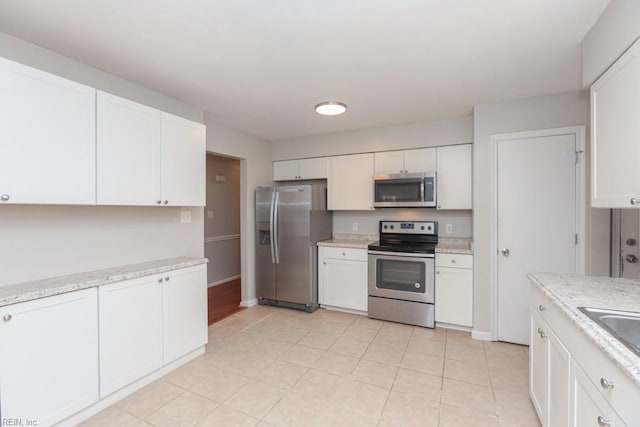 kitchen with light stone countertops, white cabinetry, and appliances with stainless steel finishes