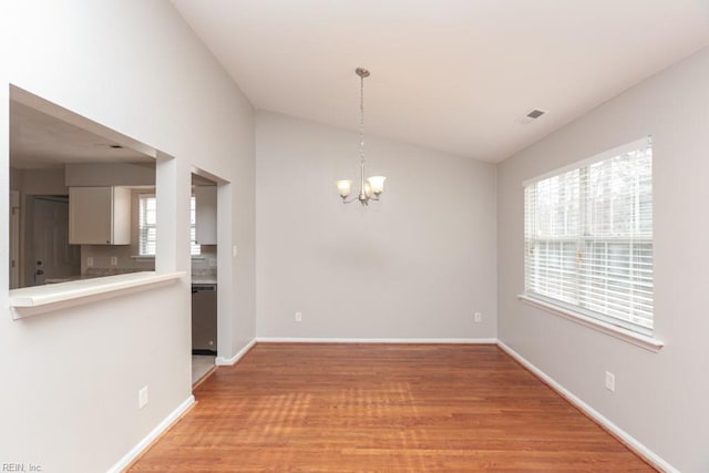 unfurnished dining area featuring lofted ceiling, light wood-type flooring, and an inviting chandelier