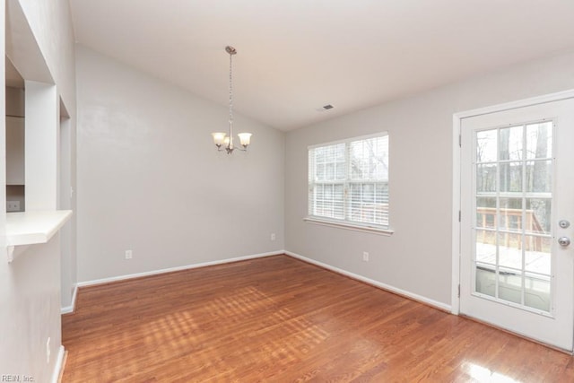 unfurnished dining area with wood-type flooring and an inviting chandelier