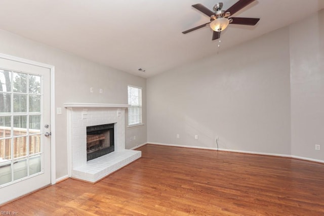 unfurnished living room featuring hardwood / wood-style floors, ceiling fan, and a fireplace