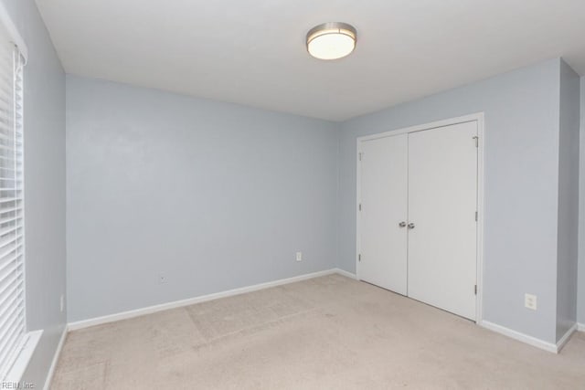 unfurnished bedroom featuring light carpet and a closet